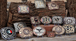 Custom belt buckles and other western accessories on tree stumps