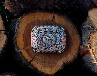 Belt buckle by Cowboss Silversmiths, sitting on a tree stump